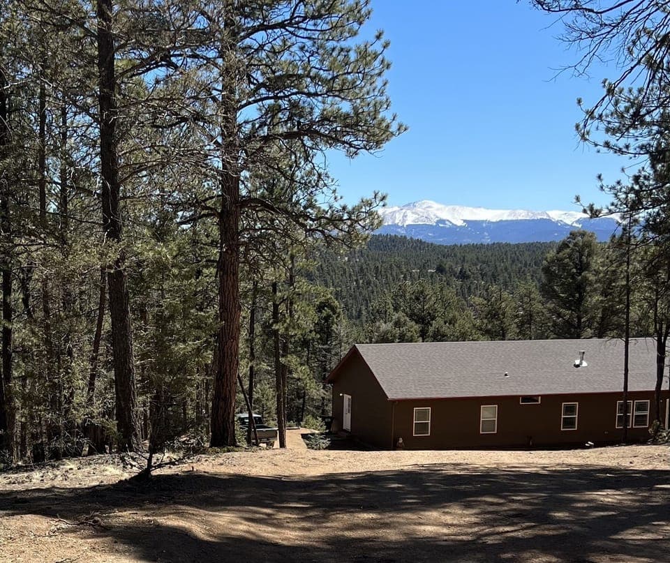 Pikes Peak towers behind TimberStar Lodge, where the trees meet the sky. 