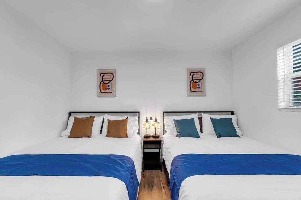 "Spacious Airbnb bedroom with two comfy beds—perfect for families, friends, or group stays. Modern decor and natural light make it feel like home."