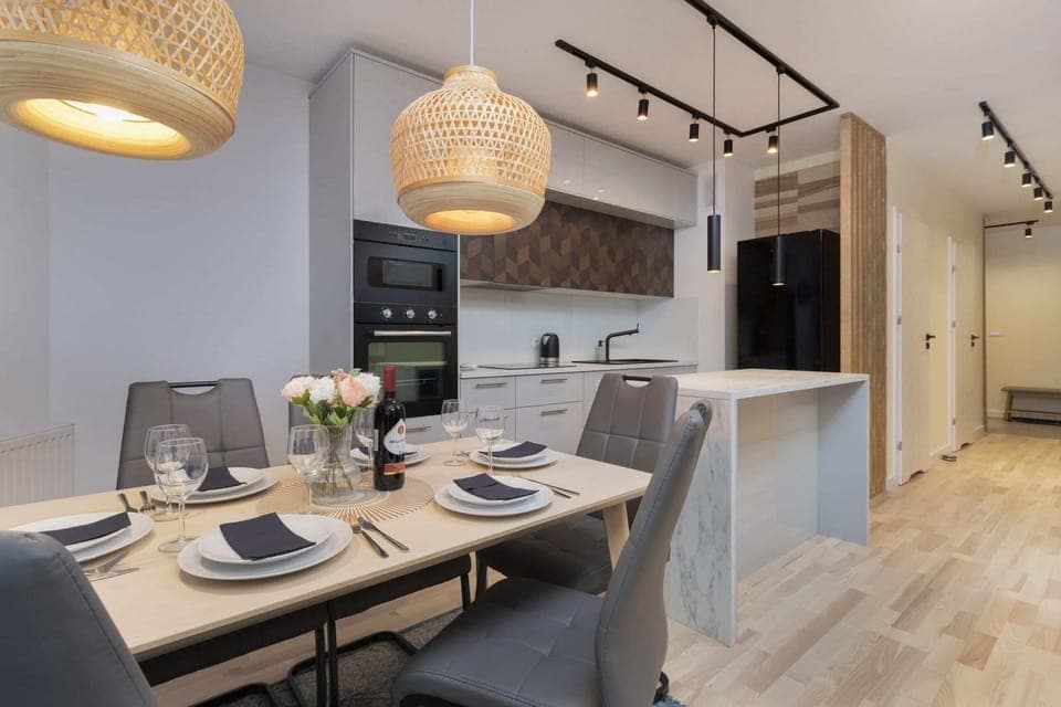 A dining table with modern chairs and elegant lighting, perfect for shared meals.