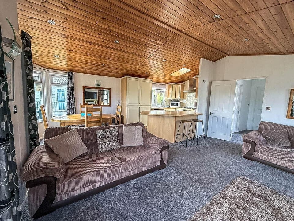 Cozy living room with rustic wood ceiling and open kitchen view