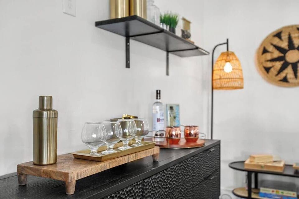 Modern bar setup with glassware and a cocktail shaker on a textured black cabinet.