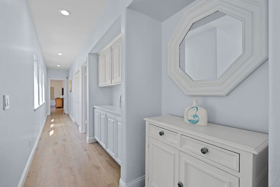 Hallway with coastal charm that connects to the bedrooms