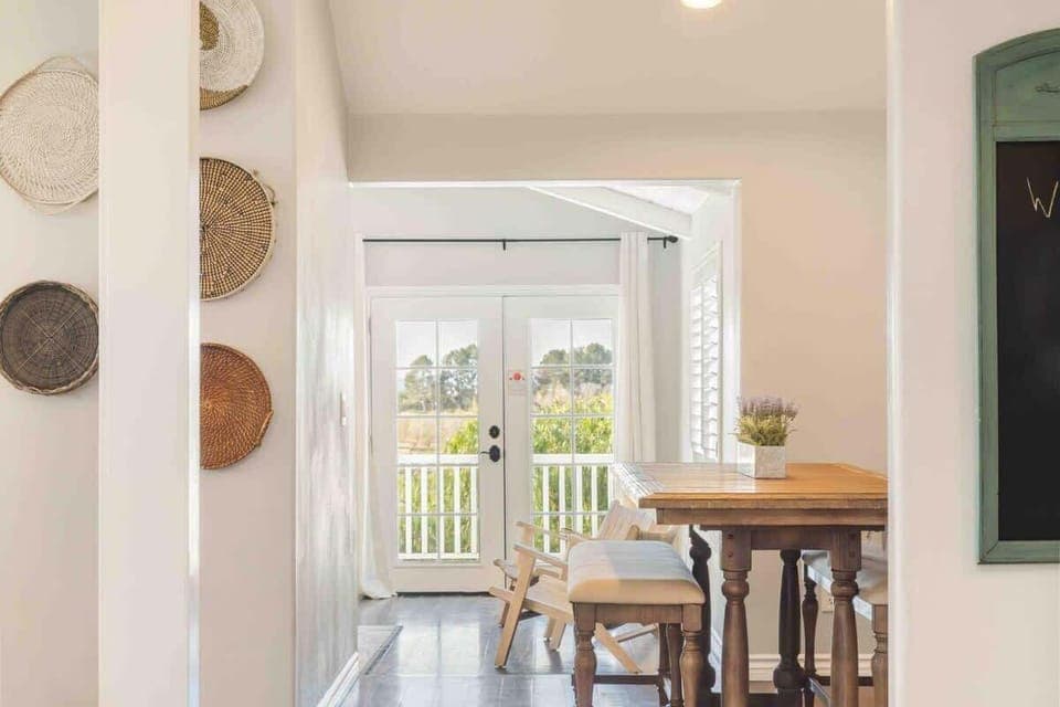 A cozy and inviting dining room, featuring a wooden dining table surrounded by two matching benches with plush cushion.