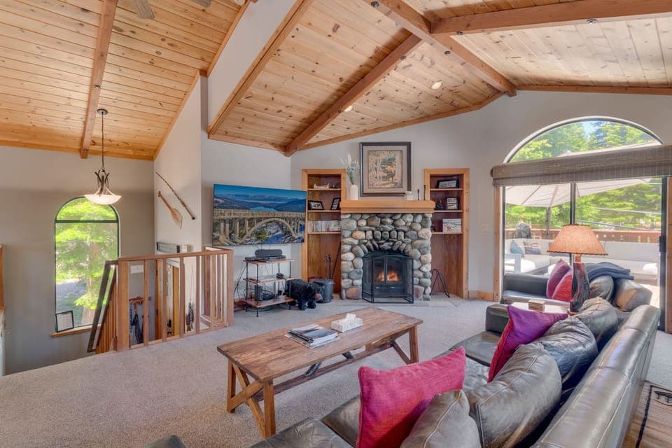 Living Room: Bright, open layout, 2 couches,  65” Smart TV, wood-burning fireplace access to deck