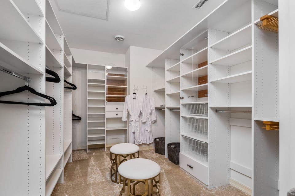 Spacious primary suite closet with extensive white shelving.