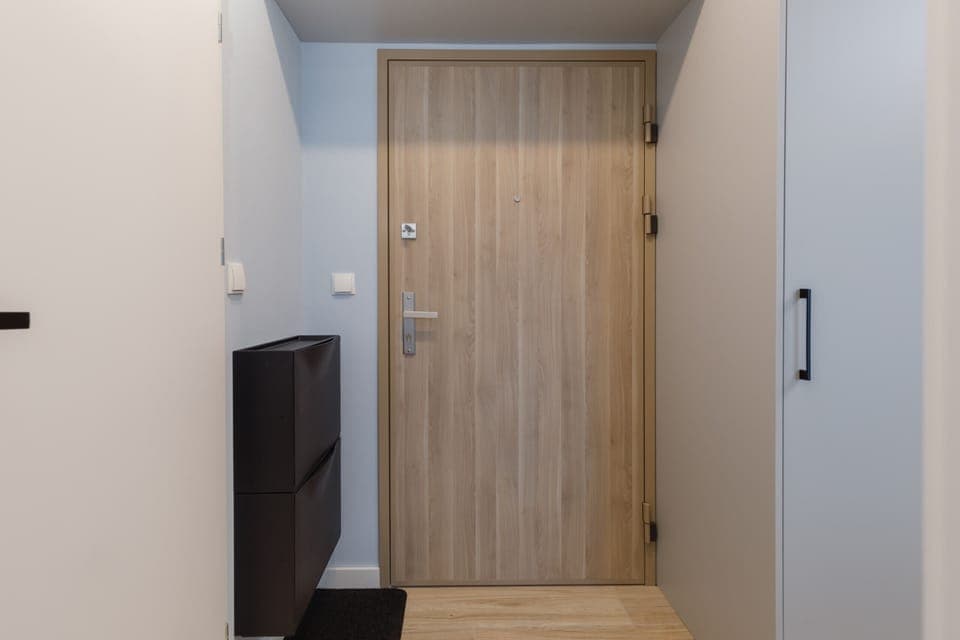 An entryway with a wooden door, minimalist design, and integrated storage.
