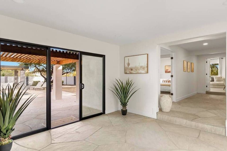 Bright entryway with large sliding glass doors opening to a shaded patio area.