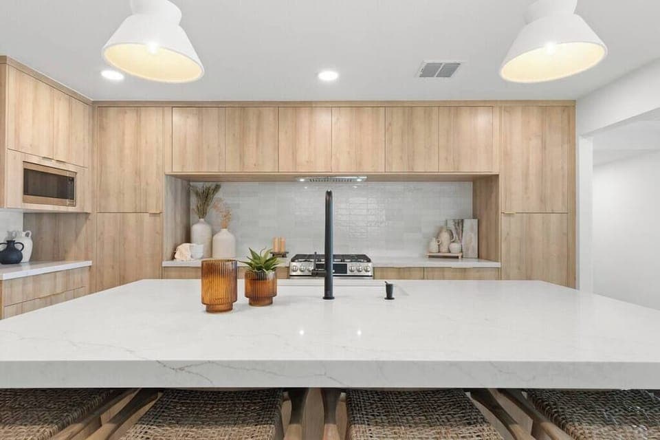 Modern kitchen with a large marble island and wood cabinetry for a clean, inviting space.