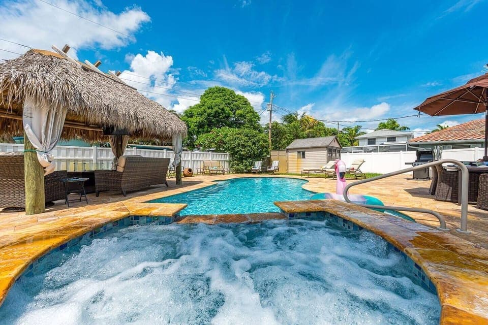 A resort-style oasis in the heart of Deerfield Beach! Large heated saltwater pool with a hot tub, rustic tiki hut with a large gas-powered firepit, string lighting & smart tv. Outdoor dining table for 6 and plenty of seating and lounging for the family.