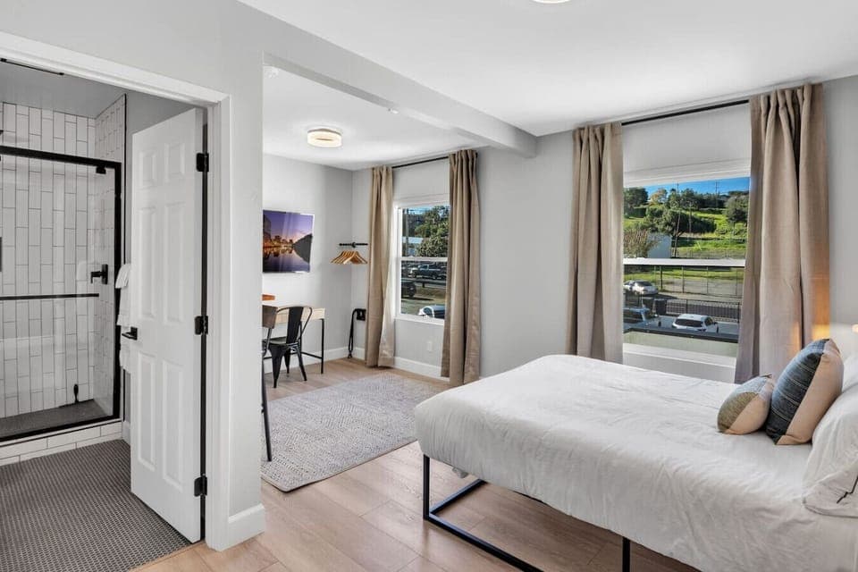 View of your comfortable queen bed and work station, with lots of natural light from the windows. We have drapes in the suite if you want less light