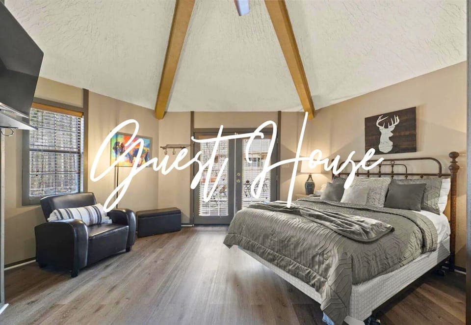 Relax in the spacious guest house bedroom, featuring a queen-sized bed, cozy seating, and stylish rustic accents for a perfect retreat.