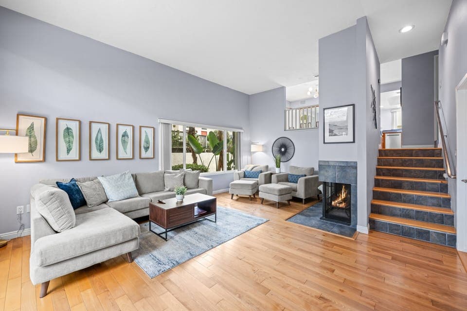 High Ceilings, Large Living area with comfortable couches & chairs, Large wall mounted TV, entertainment system, and sliding glass doors out to patio / backyard.