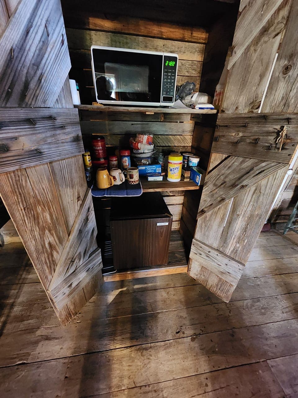 Wooden cabinet  holds microwave & Frigerator, coffee, cutlery, plates,& cups