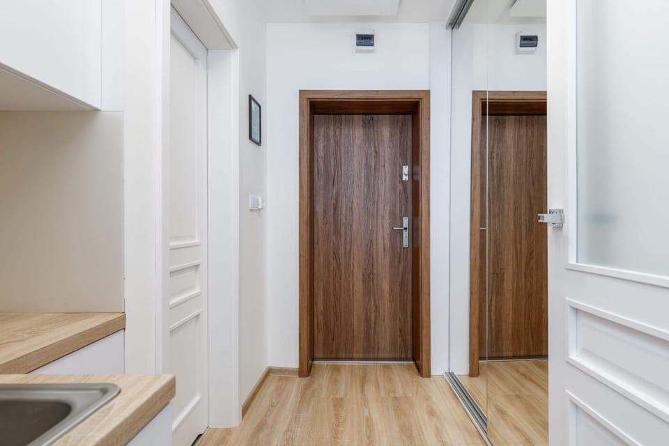 A hallway leading to wooden apartment doors, showcasing a clean and welcoming entrance.
