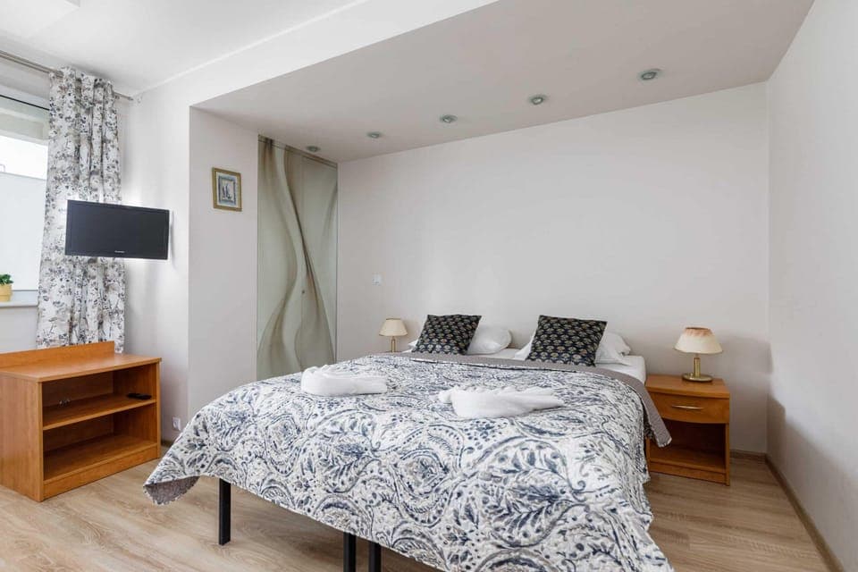 A cozy bedroom featuring a double bed with patterned bedding, wooden bedside tables, and soft lighting.
