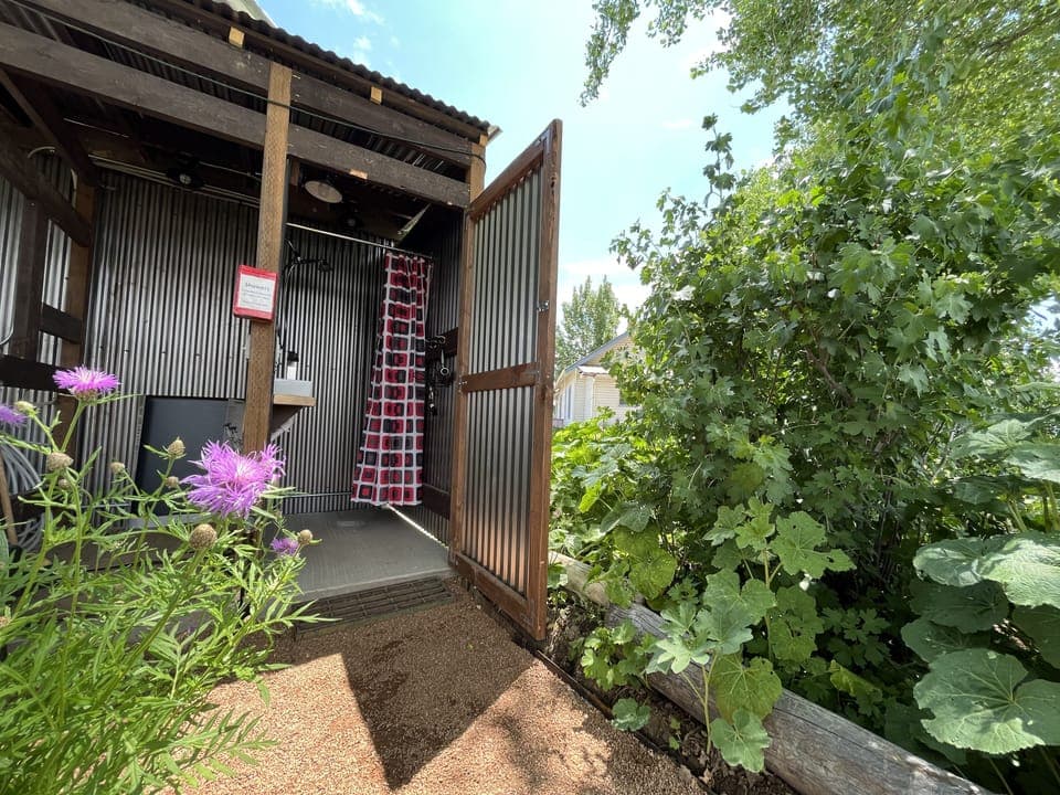 The outdoor shower has hot water, and is located behind the small blue cottage.