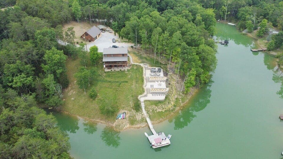 This is a drone picture from the back of the property where you can see the lake on 2 sides, the 3 patios, the kayaks free for use, the 2 large back porches, the large driveway with lots of room for parking. 