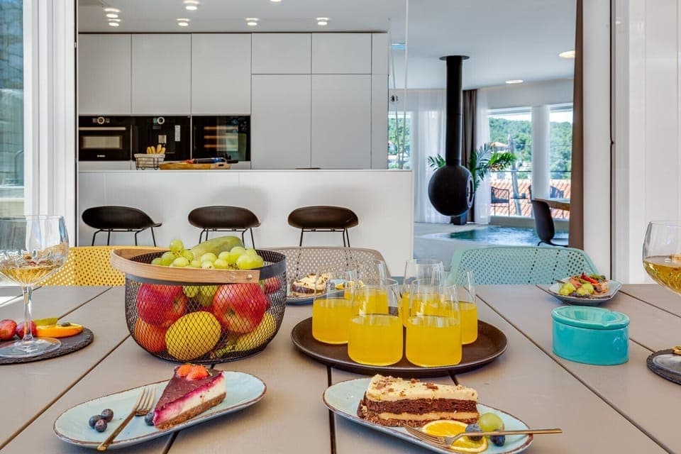 A dining table on the outdoor terrace with served cakes and a view of the interior of Croatia luxurious Ideali villas in Vrboska on Hvar