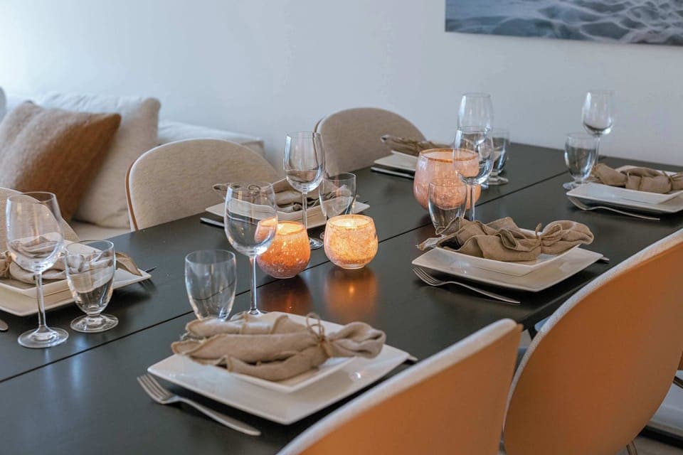 Elegant dining setup with seating for six, stylish neutral decor, soft candle lighting, and cozy pillows—perfect for intimate dinners or entertaining guests in comfort and style.