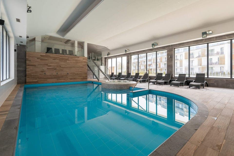 A luxurious indoor pool area with large windows, modern tiling, and a relaxing ambiance.
