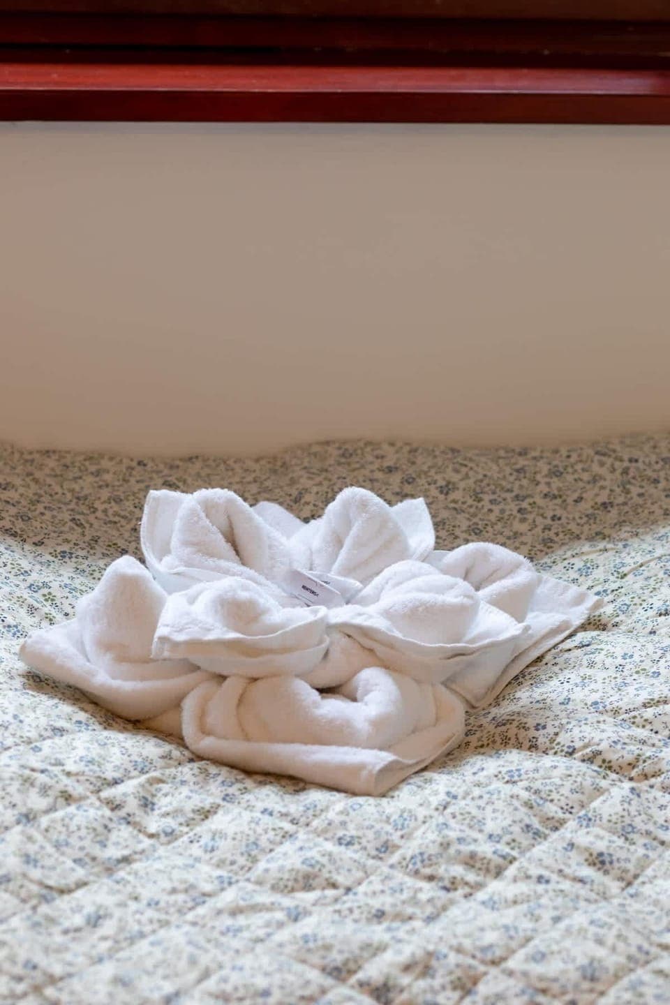 A close-up of neatly folded towels placed on the bed, accented with decorative flowers.