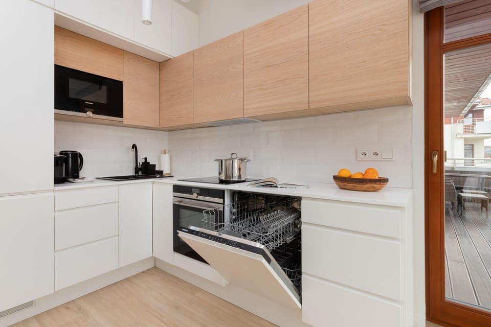 A modern kitchen with light wood cabinets, integrated appliances, and ample workspace.