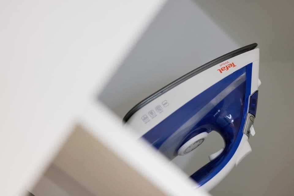 A close-up of an iron stored neatly on a shelf, providing guests with added amenities.
