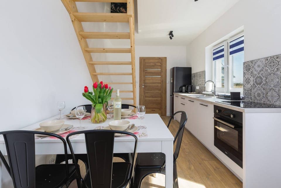 A compact yet fully equipped kitchen with white cabinetry and intricate patterned tiles on the backsplash. The space is designed for efficient meal preparation