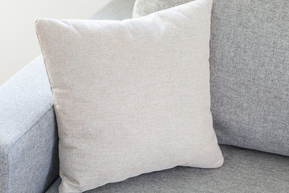 A soft, decorative pillow resting on a cozy grey sofa, adding a touch of comfort and style.