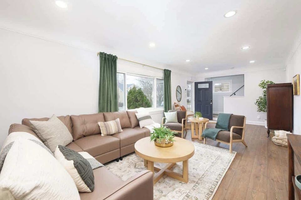 - Bright living room with sectional sofa and modern seating   - Large windows with natural light and green curtains   - Stylish setup perfect for relaxing and gathering  