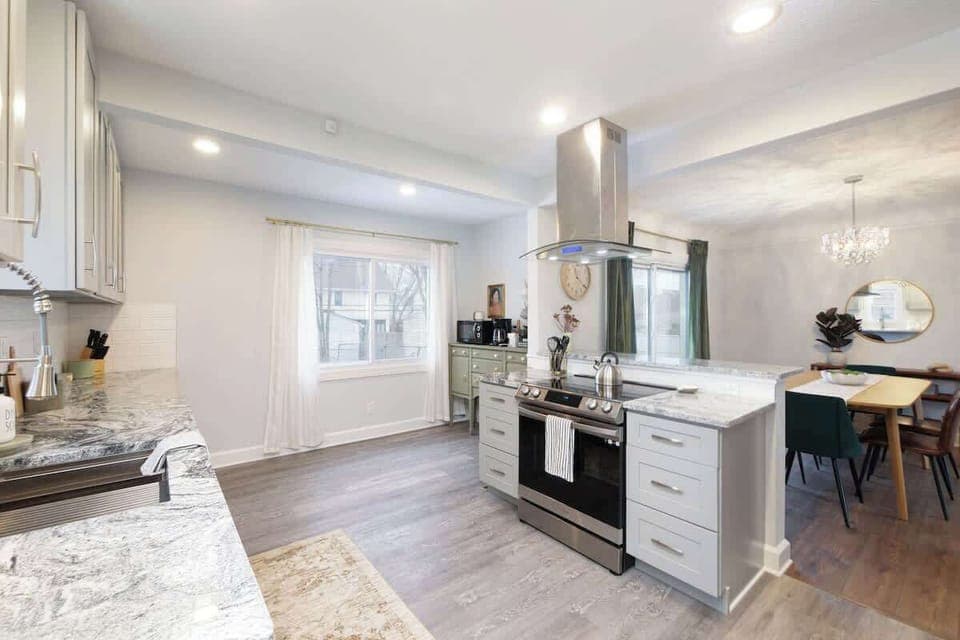 - Modern kitchen with stainless steel appliances   - Marble style counters and sleek gray cabinetry   - Open layout connects kitchen to dining area seamlessly  