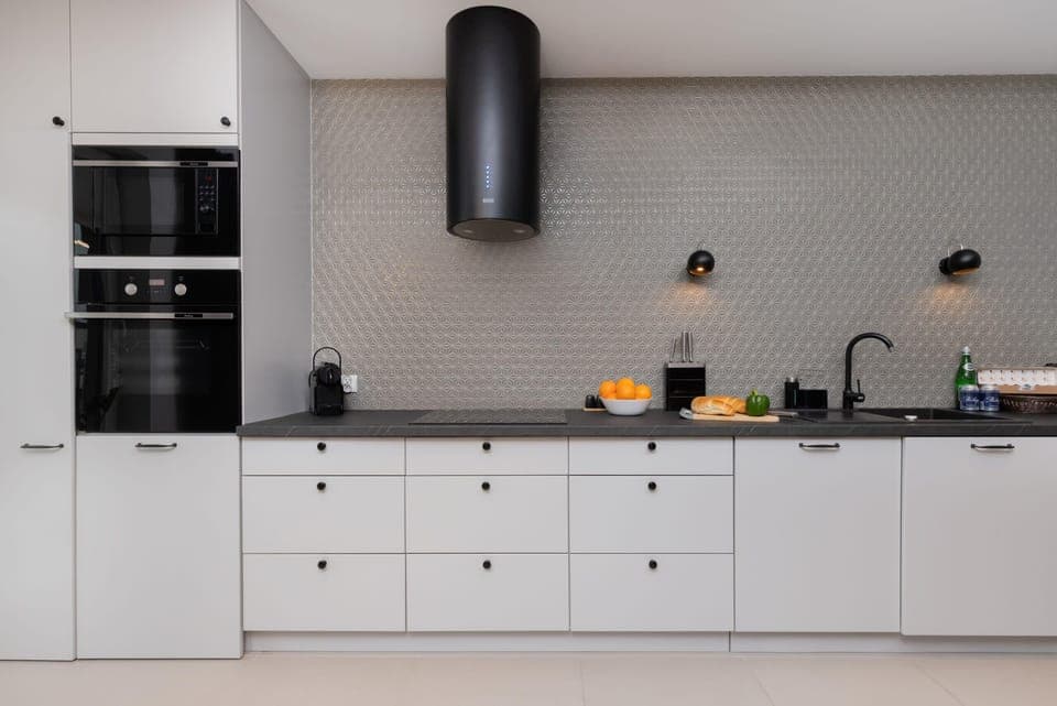 A sleek white kitchen with minimalist cabinets and black accents, featuring a functional and stylish design. The workspace is bright and well-organized.