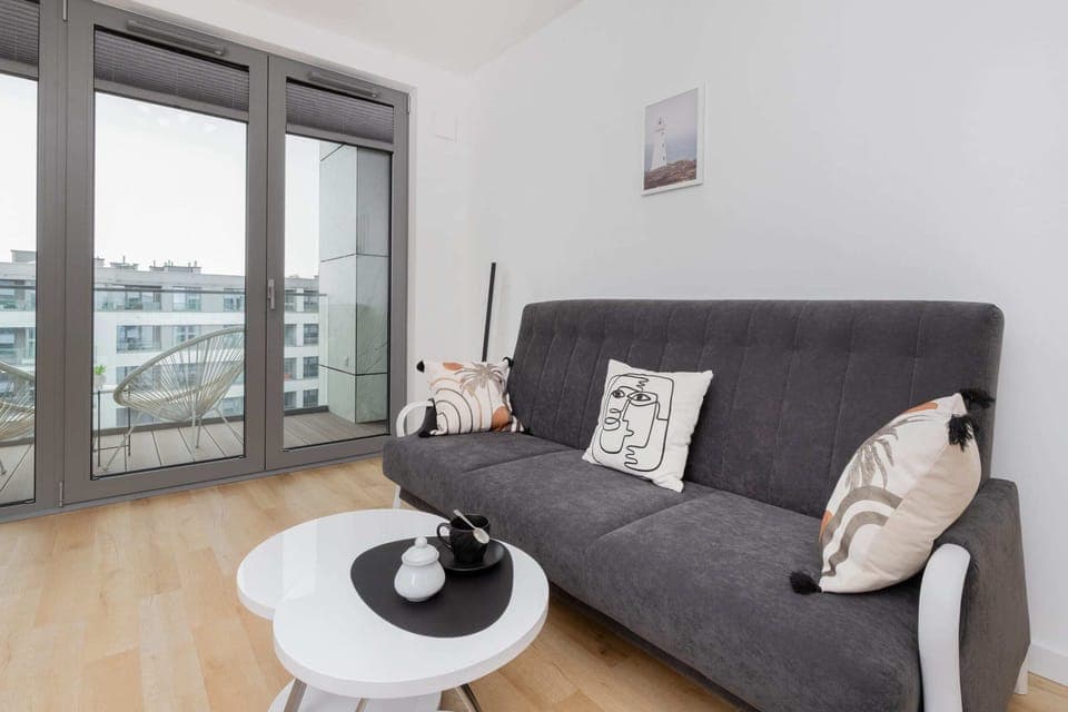 Modern living room with a comfortable grey sofa, a stylish coffee table, and large windows providing plenty of natural light.

