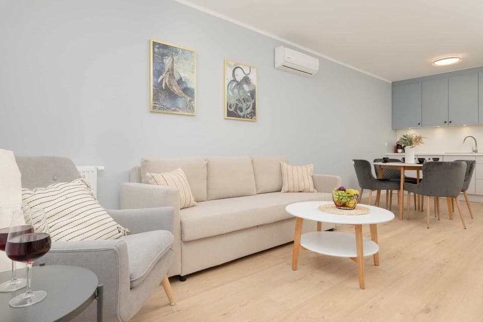 A view of the combined living and dining areas, with a comfortable sofa, dining table, and kitchenette in the background.