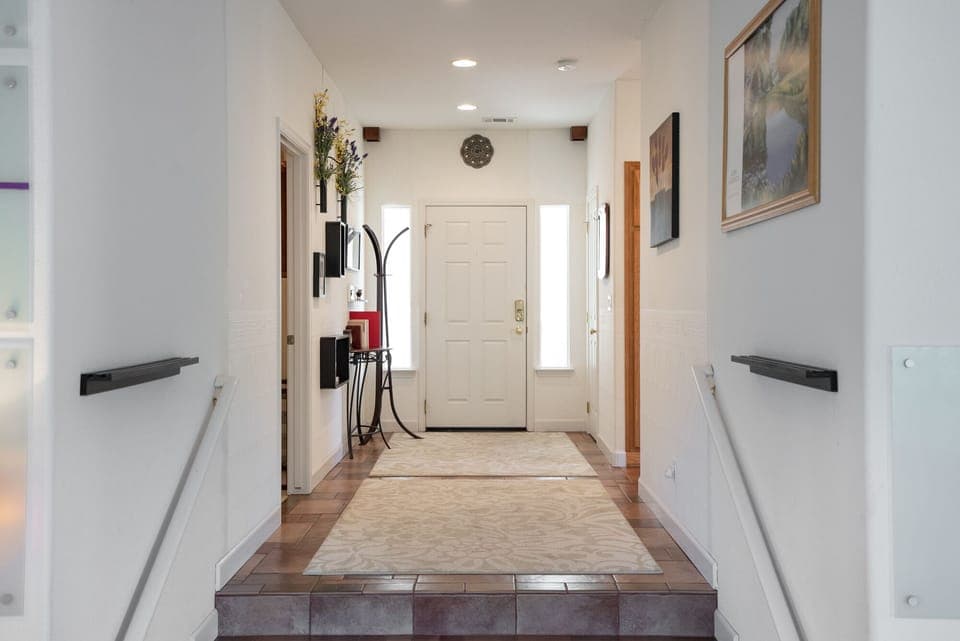 This welcoming home entryway features a classic white front door flanked by sidelight windows that bathe the space in natural light.