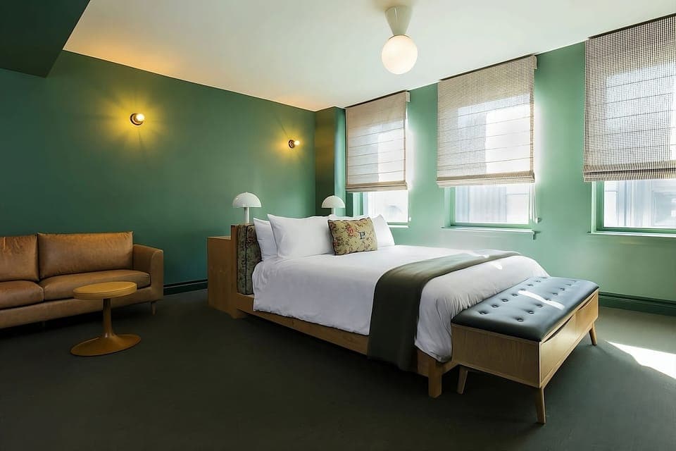 Unwind in this sunlit bedroom with plush linens and sofa.