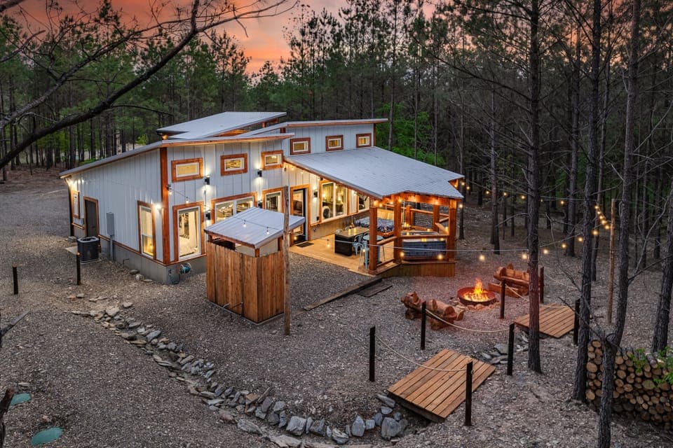 Modern rustic cabin illuminated at dusk in the pines
