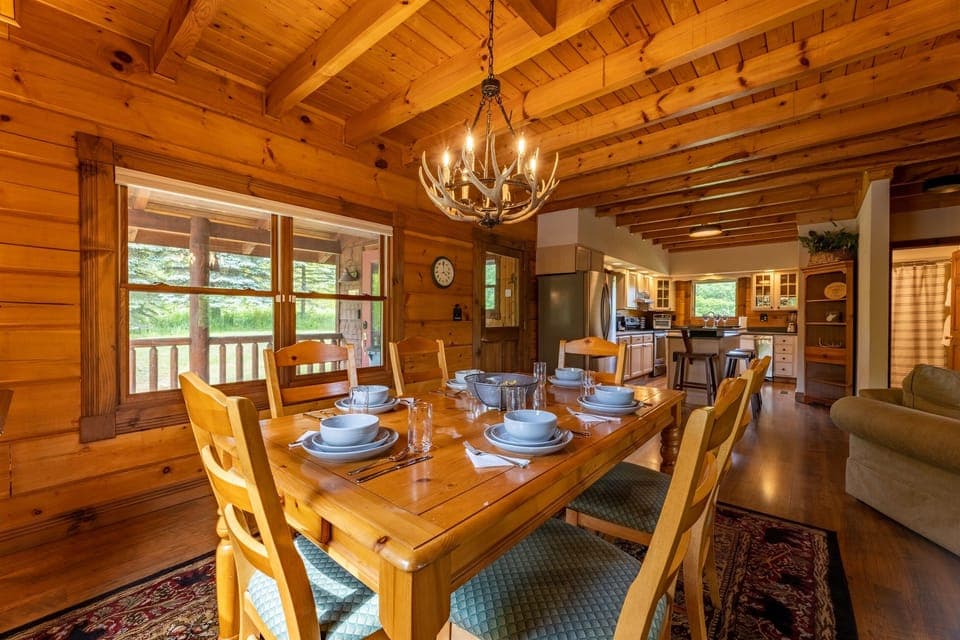 Warm and cozy dining area with antler chandelier, seating for 6 at table and 3 at the bar.