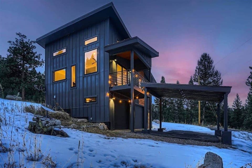 The side of the house during the winter months, with a light dusting of snow covering the ground and the surrounding greenery. The home stands warmly against the chilly air, showcasing its winter charm and inviting atmosphere.