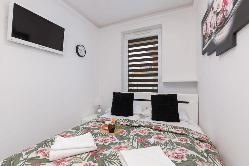 A bedroom with a comfortable double bed, floral bedding, bedside lamps, and stylish decor elements such as floral artwork on the wall.