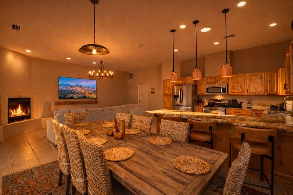 Open floor plan with kitchen, dining, living, Sonos, fireplace, bar, 85″ TV.