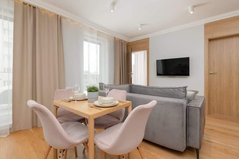 An open-concept kitchen with white cabinets, modern appliances, and a dining table with elegant chairs.