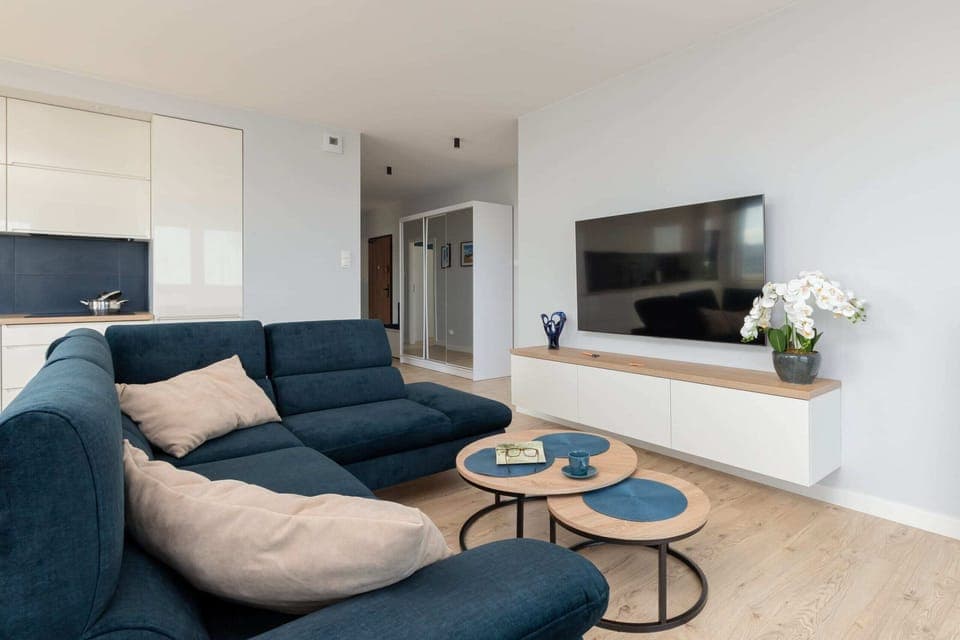 A bright and open living area featuring a large blue sectional sofa, a coffee table, and modern decor.