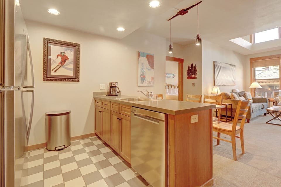 Step into your fully equipped kitchen where warm wood cabinets and stainless steel appliances create the perfect space for preparing mountain meals. Natural light flows through skylights as you cook, with cozy dining just steps away.