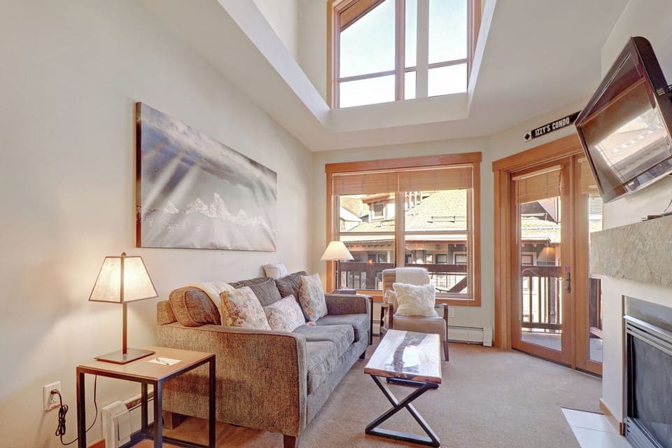 Relax in your bright, airy living space where natural light pours through the skylight above. Sink into the plush sofa while enjoying mountain views through the windows, and cozy up by the fireplace after your alpine adventures.