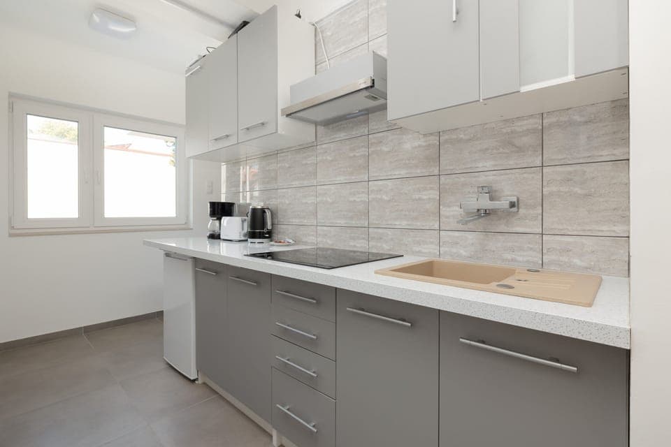 A sleek kitchen with white cabinets, a tiled backsplash, and modern appliances for a convenient stay.
