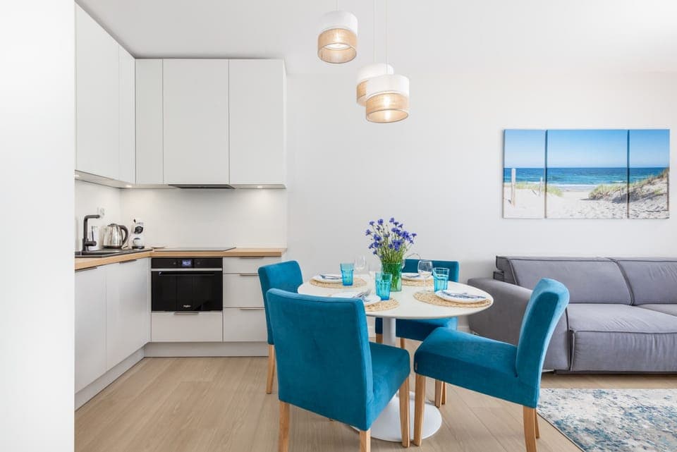 A modern living area with a wall-mounted TV, adjacent to the dining space, offering a comfortable spot to relax.

