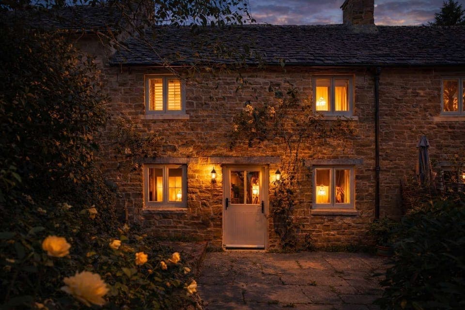 Warm sunset light falls across the front of Two Rose Walk Cottage, a classic Cotswold home near Daylesford. A peaceful first glimpse of this charming village cottage, perfectly placed for countryside walks, cosy pubs and relaxed evenings.