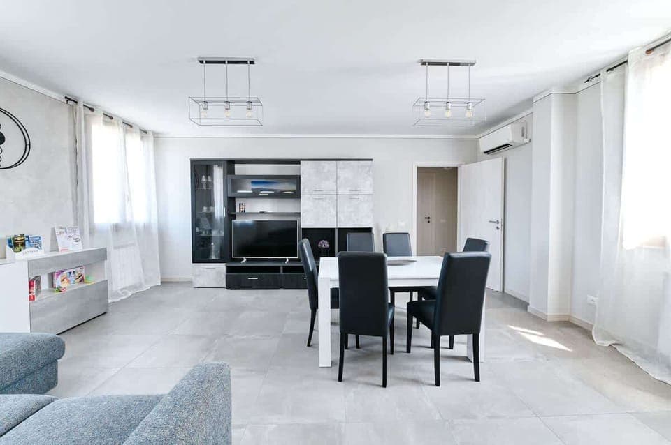 Zona Living con divano letto, mobile con Smart TV 55", tavolo da pranzo allungabile per 6 persone, climatizzatore Daikin