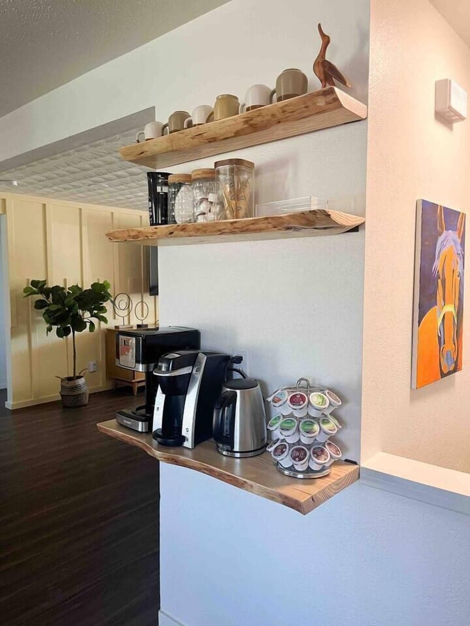 Live edge shelves with coffee pot maker, single serve coffee, coffee bean grinder, electric water kettle, milk frother, coffee filters, stirrers, sugar, half and half, French vanilla cream, hot tea packets, honey sticks.